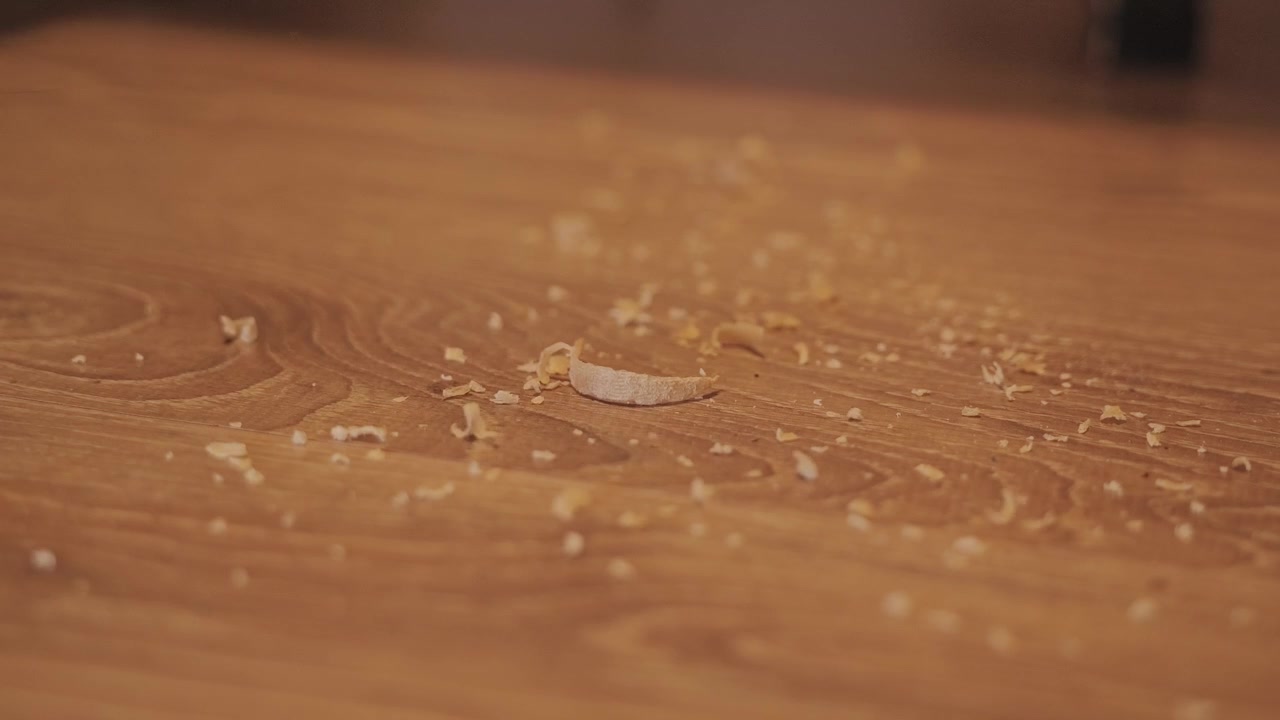 Slow motion brush sweeps peeled skin fragments, creating a metaphor for drought