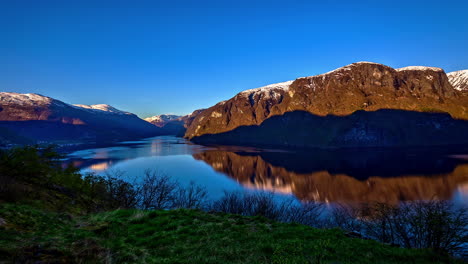 time lapse shot of beautiful sunrise in fjord surrounded by snowy mountains and blue sky - norwegian fjord,flam in norway