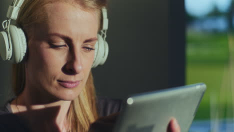 pensive woman uses digital tablet and listens to music