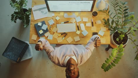 top down of black businessman celebrating achievment at office desk