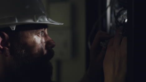 construction worker inspecting electrical panel at night