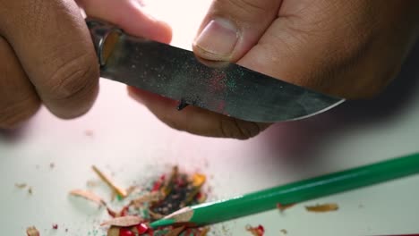 imágenes de manos afilando lentamente un lápiz y algunos lápices de colores con un cuchillo afilado