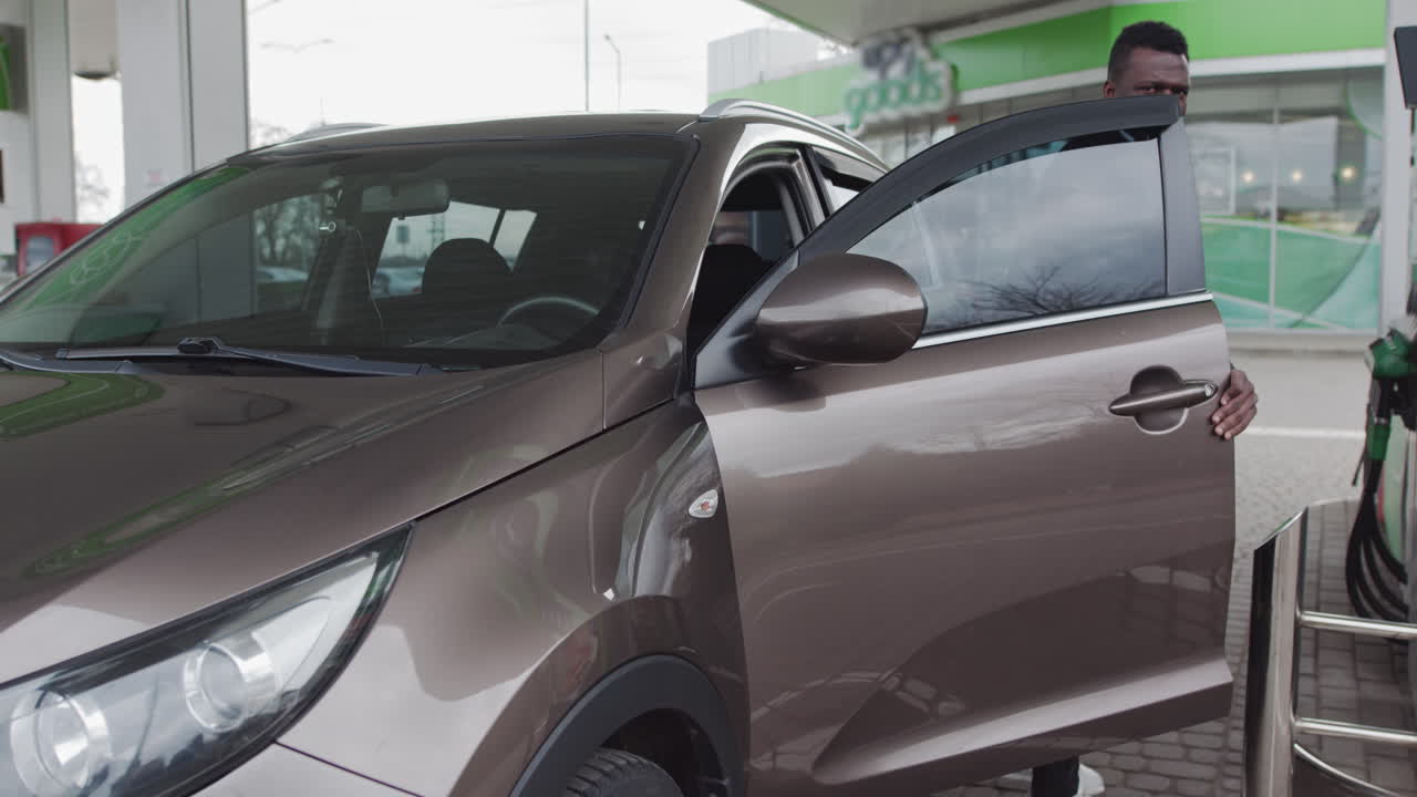 Un uomo scende dall'auto alla stazione di servizio per fare benzina