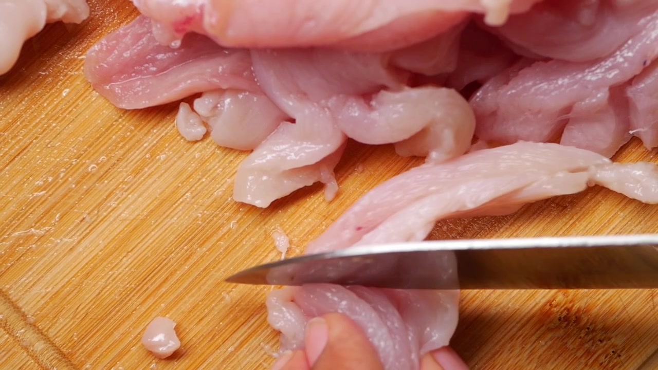 Chef che affetta pollo crudo su un tagliere di legno