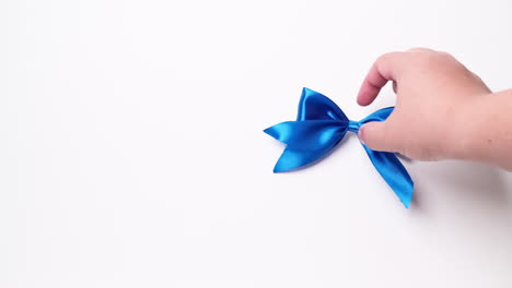 detail of male hand placing ribbon in blue color over white background