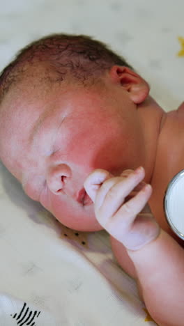 doctor in gloves listening a baby with stethoscope. naked newborn baby waving hands. top view close up. vertical video