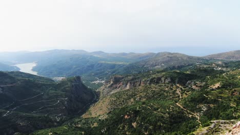 AERIAL:-Revealing-a-beautiful-landscape-with-mountain,-lakes-and-curved-road