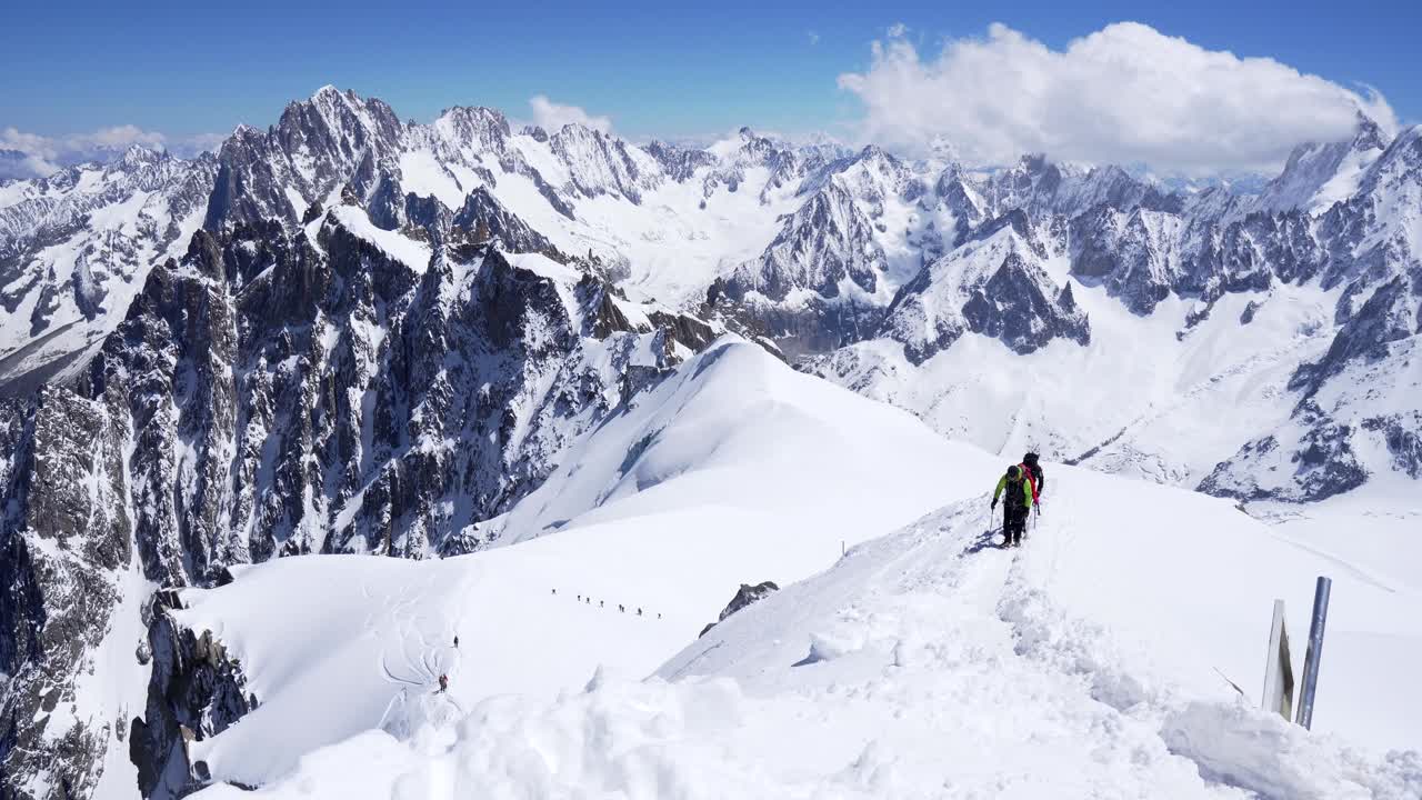 A group of climbers on their shoulders rises to the top of a snow-covered mountain. Alpine mountains Aigiullie du midi