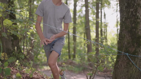 a boy in a summer camp hike overcomes an obstacle by crawling on the ground and tumbling. fun children's challenges