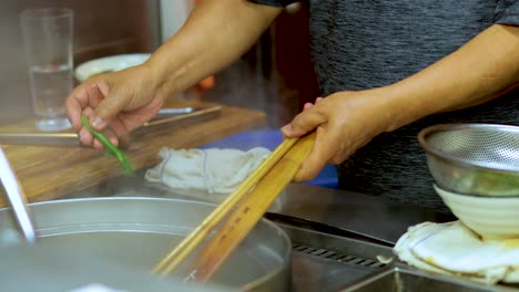 chef cooking noodle soup with meatballs