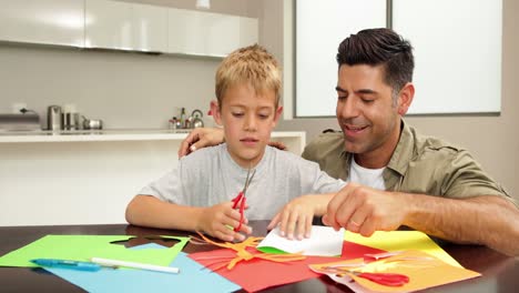 padre e hijo haciendo artes y artesanías en la mesa de la cocina