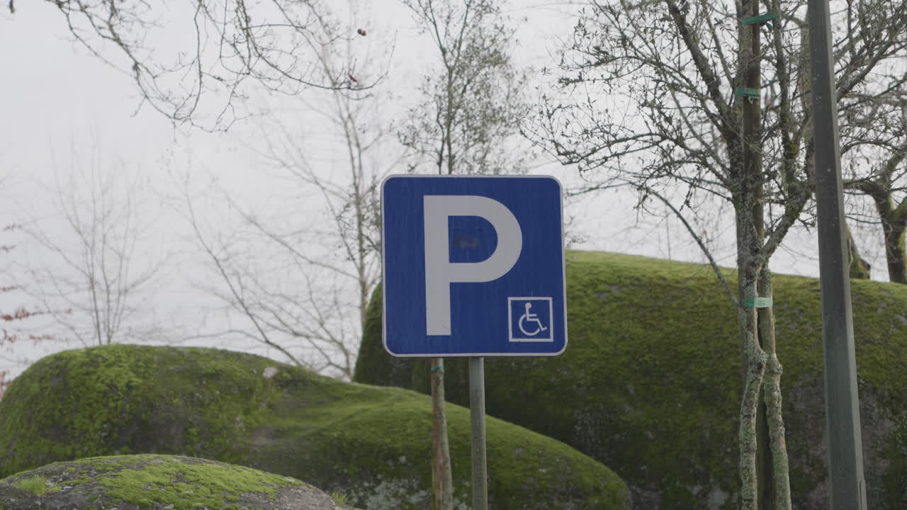 Close-up de placa de estacionamento acessível em poste em ambiente rural ao ar livre.