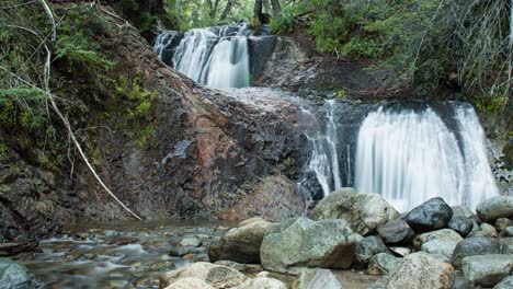 Cascada-De-Elfos-De-Lapso-De-Tiempo-En-Bariloche,-Patagonia-Argentina,-Con-Dos-Cascadas-Y-Un-Pequeño-Arroyo-Entre-Madera-Y-Rocas