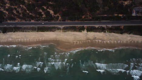 Coastal-Vietnam-road-and-sandy-beach-with-ocean-waves-rolling-towards