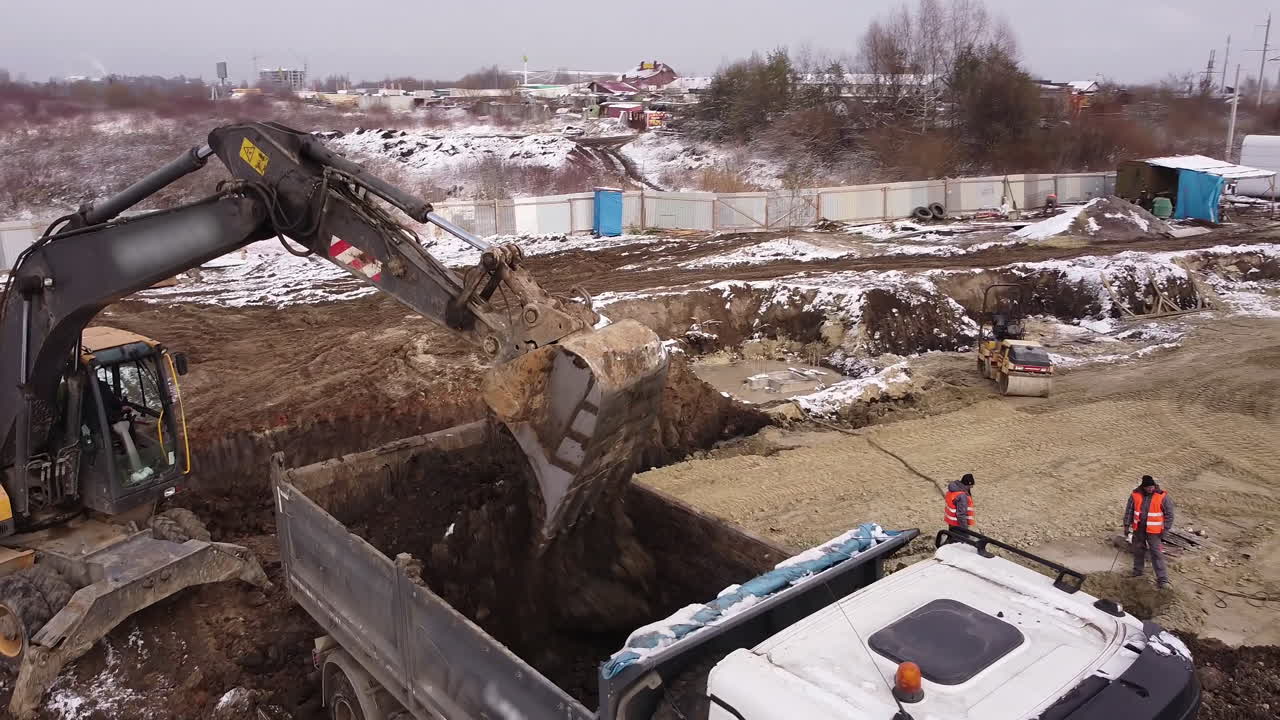 Winter Construction Site with Excavators and Dump Trucks