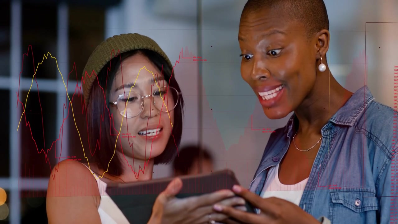 Two women workmates showing tablet, leaning, reviewing tech data with moving graphs over screen
