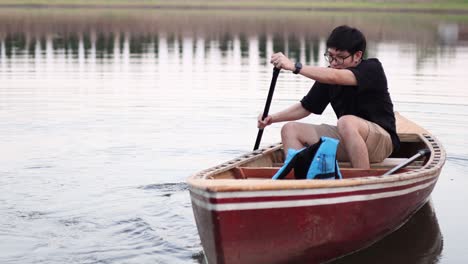 person rowing a wooden boat with a paddle