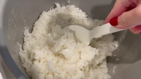 sticky white rice being scooped into a bowl right out of a rice cooker