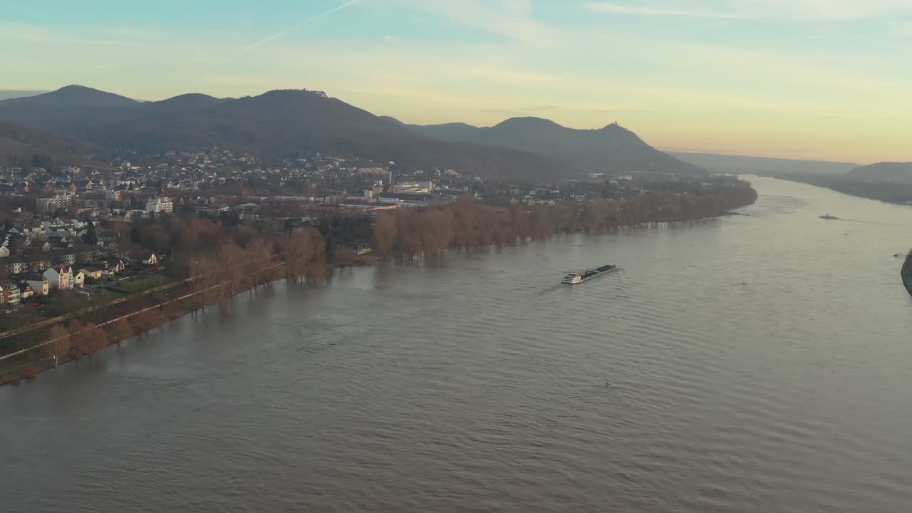 Cinematic drone -aerial shot of the river rhine with a ship and the panorama of the seven mountains - Siebengebirge Königswinter - Bonn at golden hour, 25p