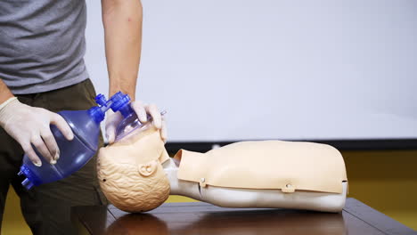 training in medical center. person in protective gloves giving breath exercise on a dummy. education on a mannequin for giving first aid.