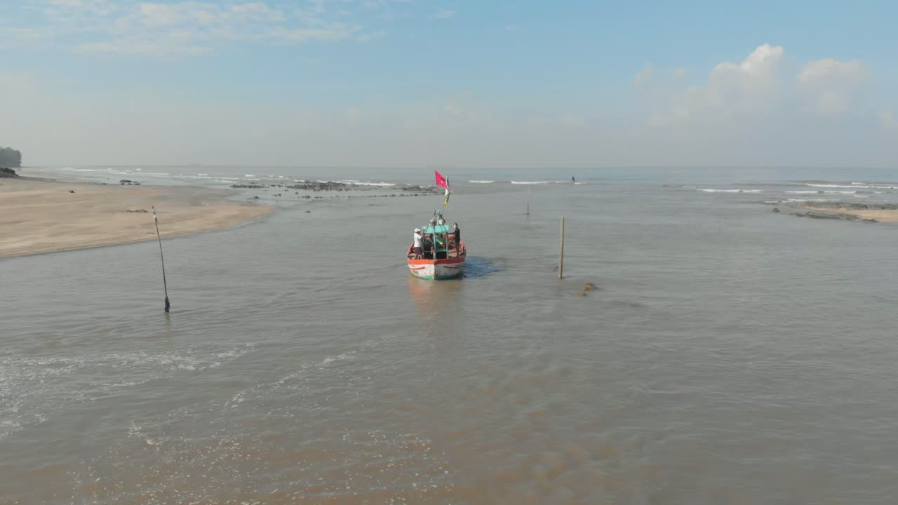 disparo de drones de un pequeño barco de pesca indio colorido que sale de un muelle de playa