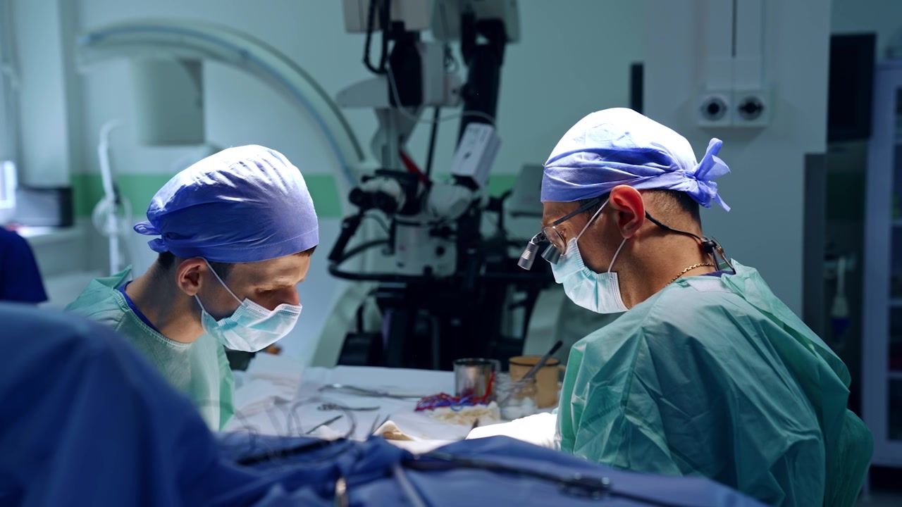 Doctor and assistant perform operation. Concentrated medics working in modern surgery room.