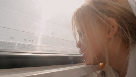 young girl in camper van looking out window at bright sunlight