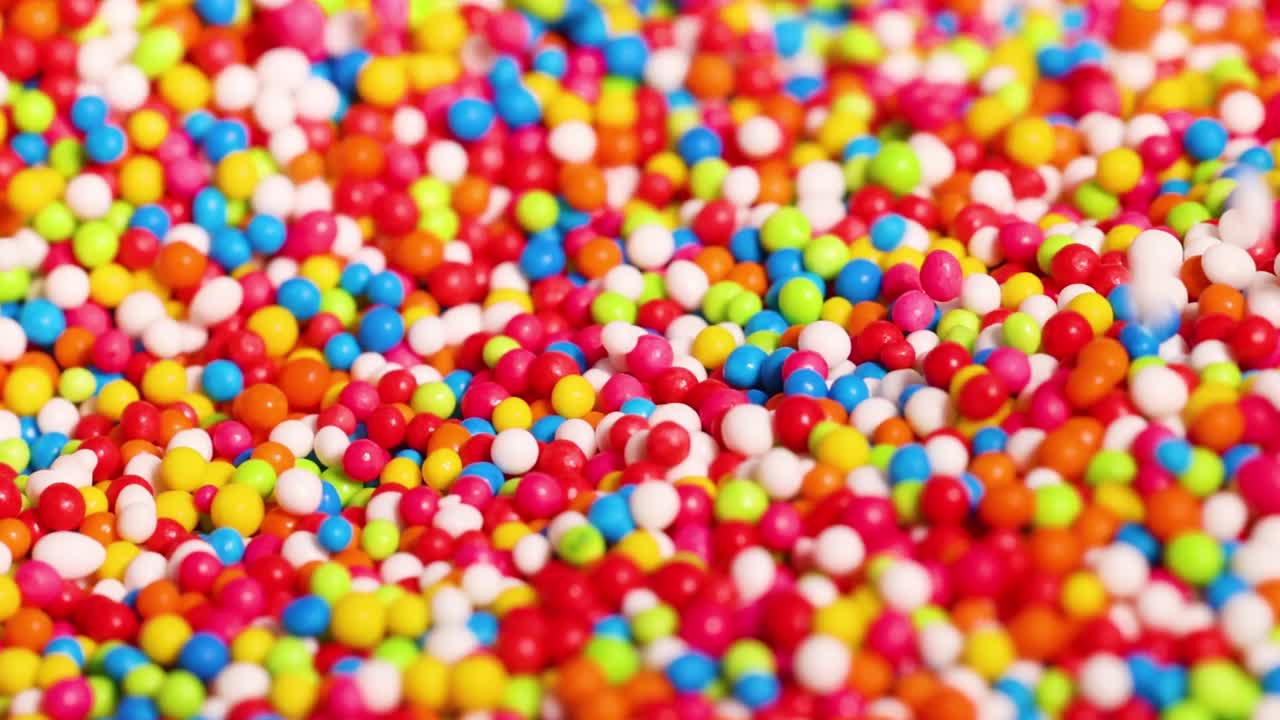 Close-up of fingers interacting with a vibrant mix of colorful candy sprinkles.