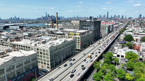 aerial flight over busy highway in industry city district of brooklyn and beautiful skyline in background