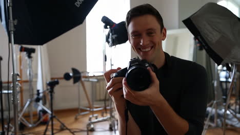smiling man holding a camera in a photography studio