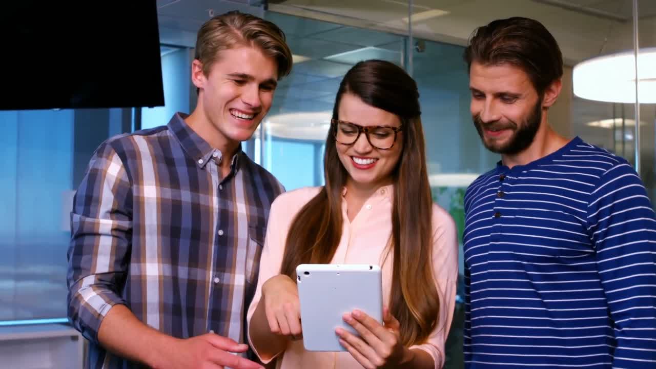 Colegas sorridentes discutindo sobre o tablet digital no escritório