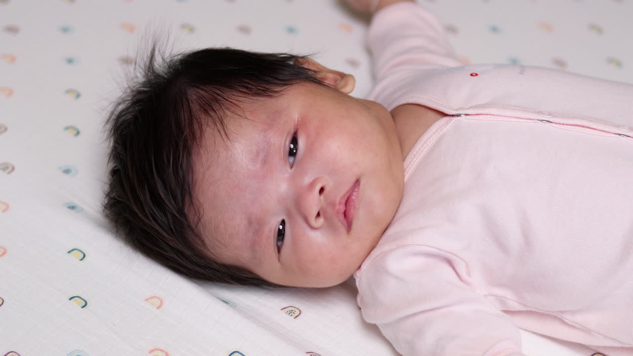 불과 몇 달 전에 태어난 아기 소녀는 방 주변의 물체와 사람들을 집중적으로 쳐다보고 있습니다.