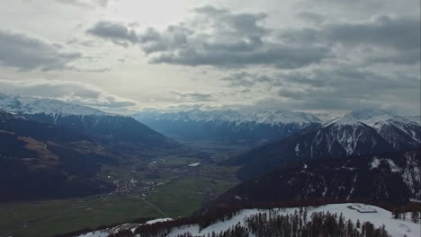 Village-in-green-valley-between-snowy-mountains-on-cloudy-day