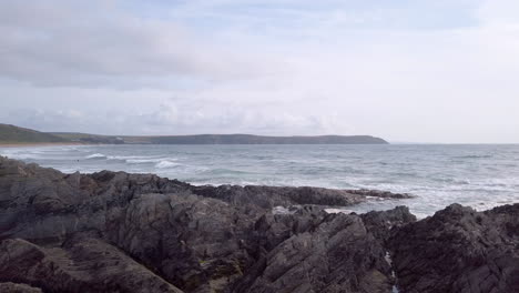 panning in from the atlantic ocean to reveal a rocky shoreline - sandy beach in slow motion