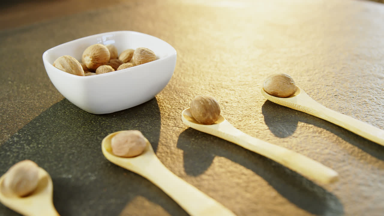 Nutmeg arranged in wooden spoon and bowl 4k