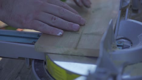 slow motion shot of pine wood being cut on a mitre saw