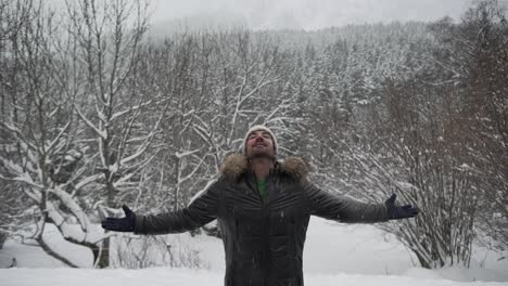 hombre contenido en ropa de abrigo extendiendo los brazos en el bosque de invierno