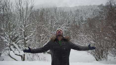 content man in outerwear outstretching arms in winter forest