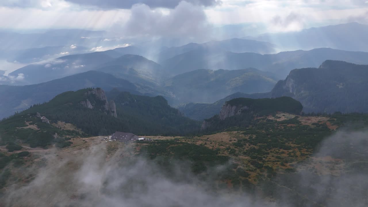 Drone rotates around Dochia cabin in Ceahlău Mountains, passing through clouds