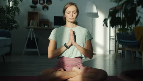woman meditating in lotus pose at home