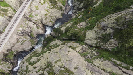 Toma-Aérea-Superior-De-Un-Desfiladero-De-Montaña-A-Través-Del-Cual-Fluye-Un-Río-Caudaloso