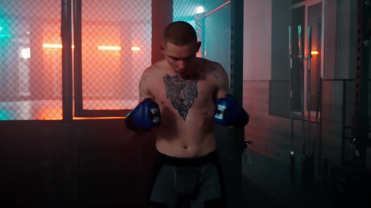 Giovane lottatore di MMA che si riscalda in una gabbia illuminata al neon.