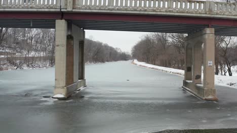 Flying-under-small-bridge-past-touristic-boat-on-frozen-river