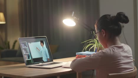 asia teen girl student distance learning with online teacher on computer screen from home at night