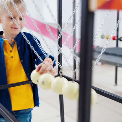 boy makes an experiment with newton's pendulum. the concept of physics. museum of science