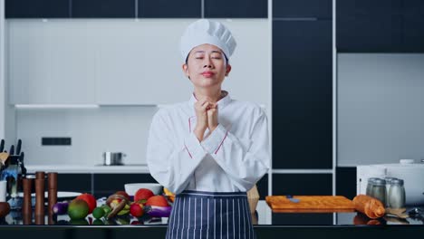 chef in prayer pose in a kitchen