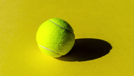 tennis ball with strong shadow on a green, yellow and orange background. simple stop motion sport animation