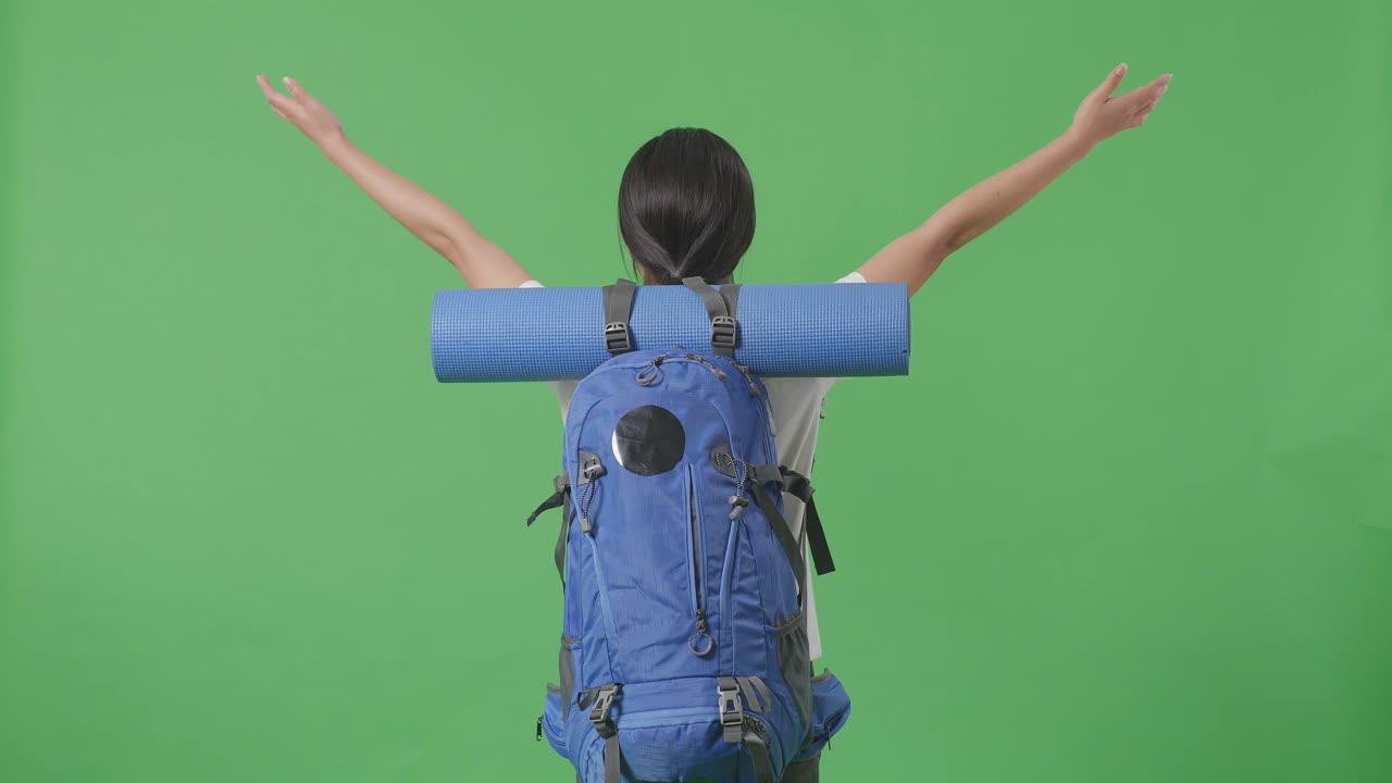 mujer con mochila y estera de yoga, brazos extendidos, en pantalla verde