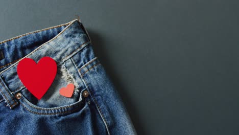 Close-up-of-jeans-with-red-hearts-on-grey-background-with-copy-space