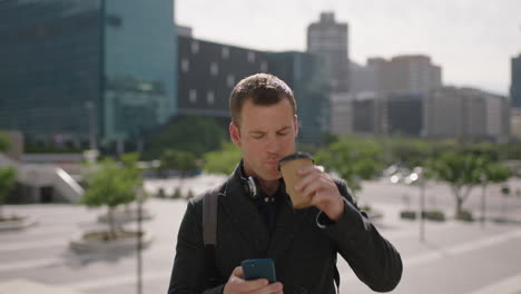 retrato de un atractivo joven hombre de negocios caucásico enviando mensajes de texto navegando usando un teléfono inteligente aplicación de redes sociales bebiendo café bebida ciudad urbana fondo